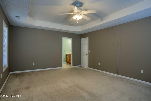 carpeted spare room with ceiling fan and a raised ceiling