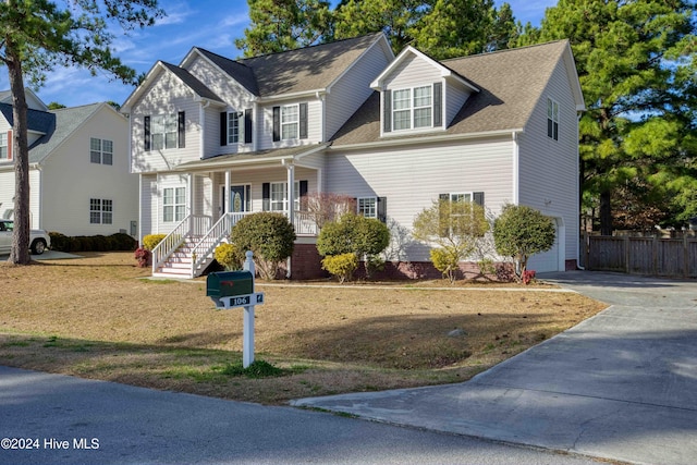 view of front facade featuring a garage, covered porch, and a front yard