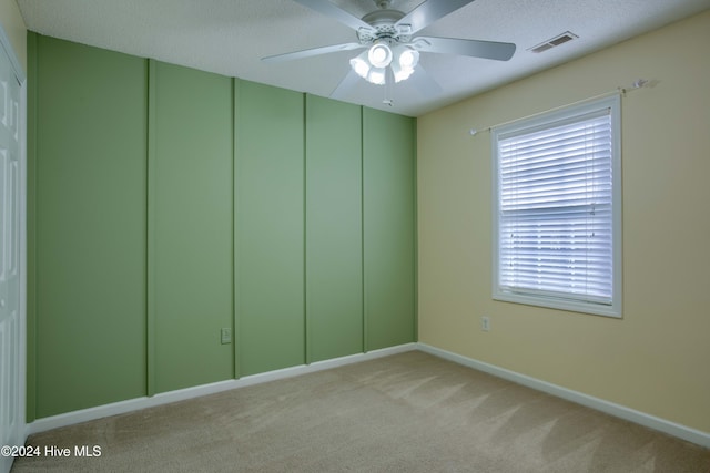 carpeted spare room featuring ceiling fan and a textured ceiling