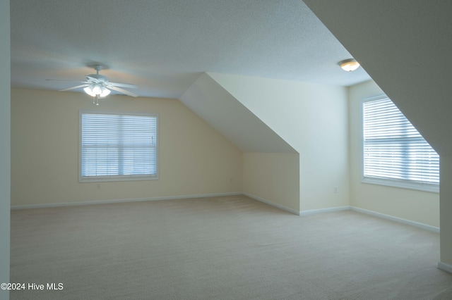 additional living space with light carpet, a textured ceiling, ceiling fan, and lofted ceiling