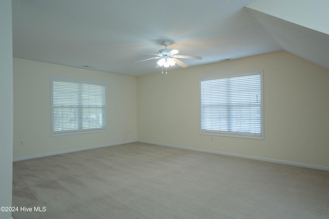 spare room featuring a textured ceiling, light colored carpet, ceiling fan, and lofted ceiling