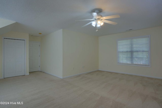 carpeted spare room with ceiling fan and a textured ceiling