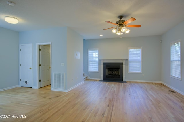 unfurnished living room featuring ceiling fan, a healthy amount of sunlight, a textured ceiling, and light wood-type flooring