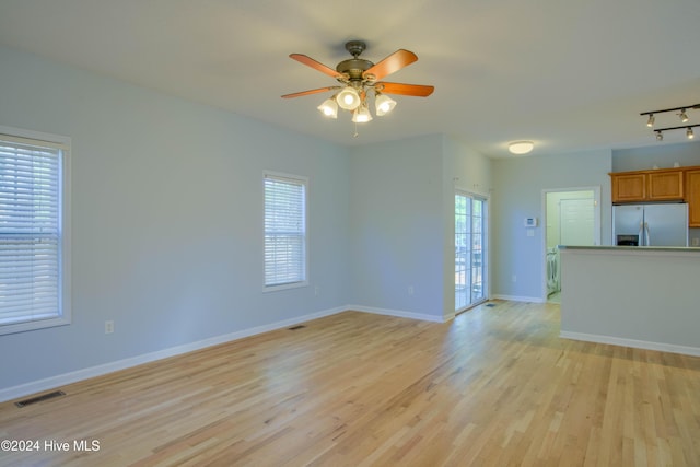 unfurnished living room with ceiling fan, track lighting, and light hardwood / wood-style flooring