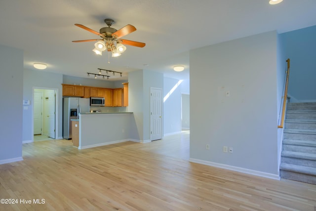 unfurnished living room with ceiling fan, rail lighting, and light wood-type flooring