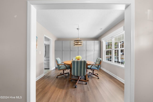 dining space featuring a notable chandelier, a textured ceiling, and light hardwood / wood-style flooring