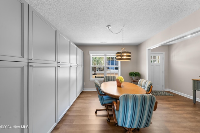 dining room with light hardwood / wood-style flooring, a textured ceiling, and an inviting chandelier