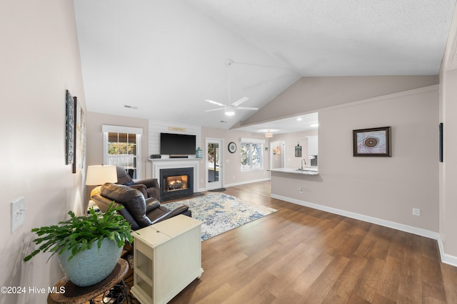 living room with ceiling fan, sink, a textured ceiling, vaulted ceiling, and hardwood / wood-style flooring