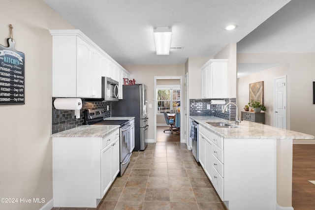 kitchen featuring sink, light stone countertops, tasteful backsplash, white cabinetry, and stainless steel appliances