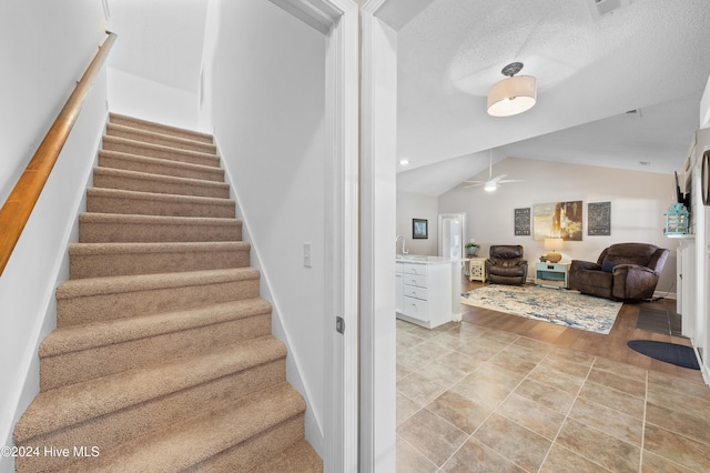 stairway with ceiling fan and vaulted ceiling