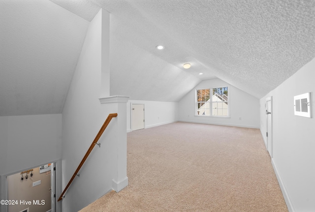 bonus room with a textured ceiling, light colored carpet, and lofted ceiling