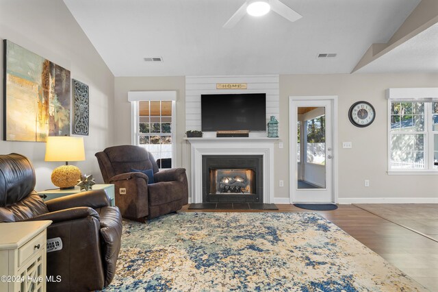 living room featuring ceiling fan, a large fireplace, lofted ceiling, and dark wood-type flooring