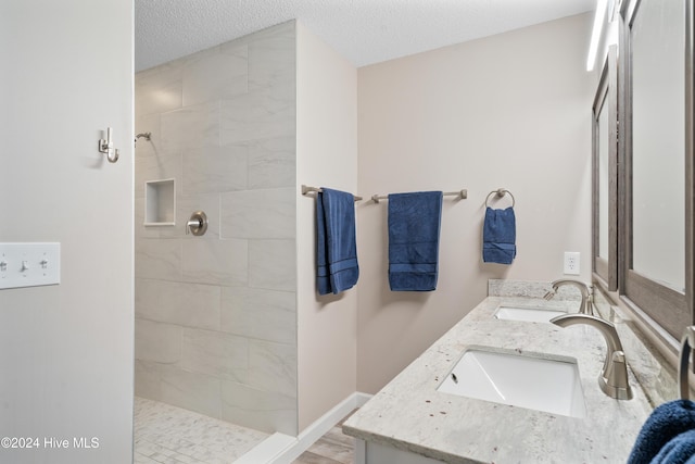 bathroom featuring tiled shower, a textured ceiling, and vanity