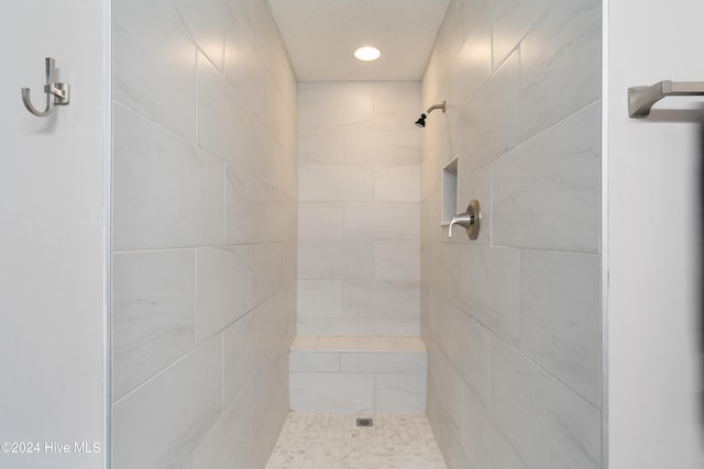 bathroom with a tile shower and a textured ceiling