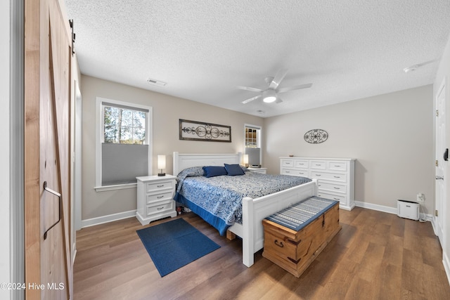 bedroom featuring ceiling fan, dark wood-type flooring, and a textured ceiling