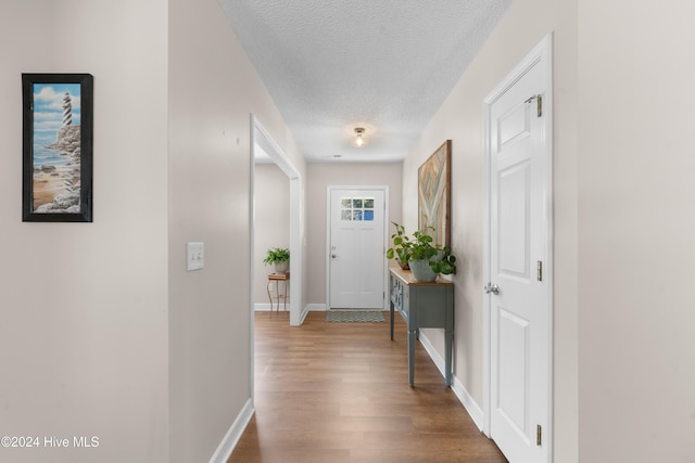 hallway with a textured ceiling and hardwood / wood-style flooring