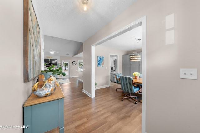 entrance foyer with wood-type flooring, a textured ceiling, ceiling fan, and lofted ceiling