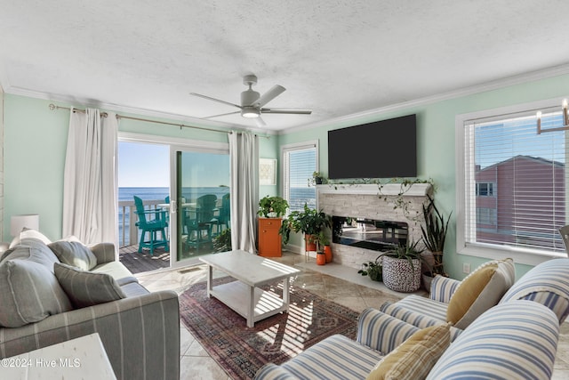 tiled living room with a fireplace, plenty of natural light, ornamental molding, and ceiling fan