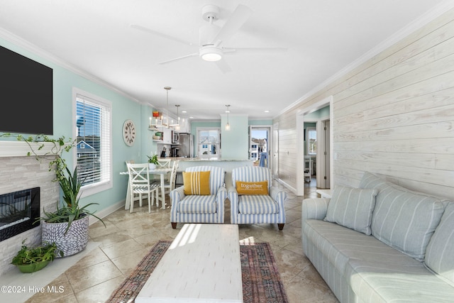 living room with ceiling fan, ornamental molding, light tile patterned floors, and a tiled fireplace