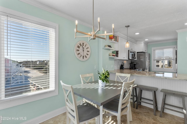 tiled dining room featuring a textured ceiling, crown molding, sink, and an inviting chandelier