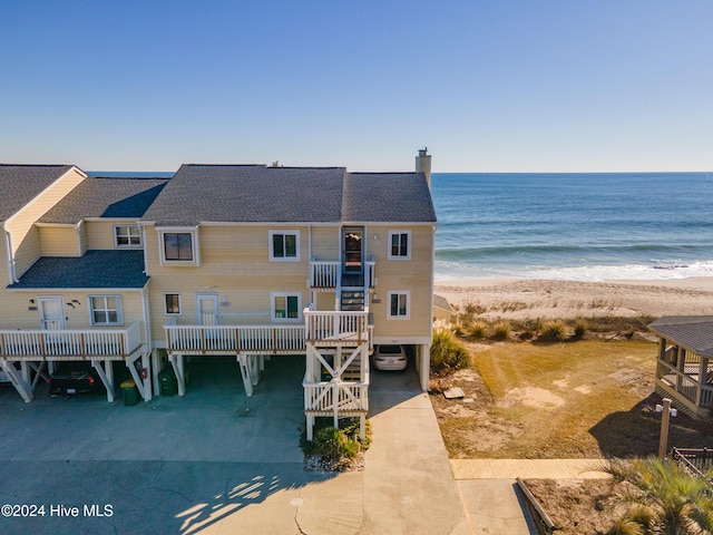 rear view of property featuring a beach view, a water view, and a carport