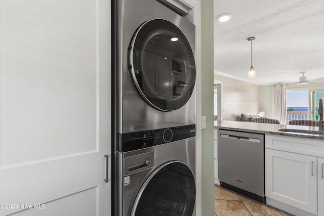 washroom with ceiling fan, sink, a textured ceiling, stacked washer / drying machine, and light tile patterned floors