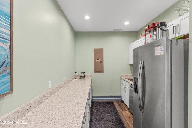 kitchen with light stone counters, stainless steel appliances, dark wood-type flooring, electric panel, and white cabinetry