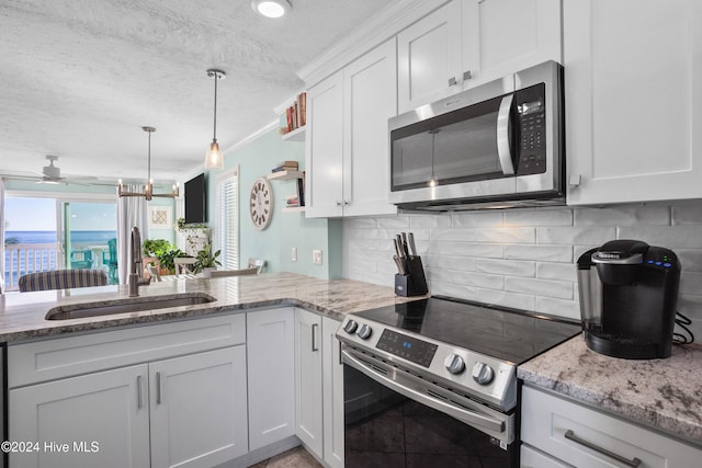 kitchen with sink, a textured ceiling, appliances with stainless steel finishes, white cabinetry, and kitchen peninsula