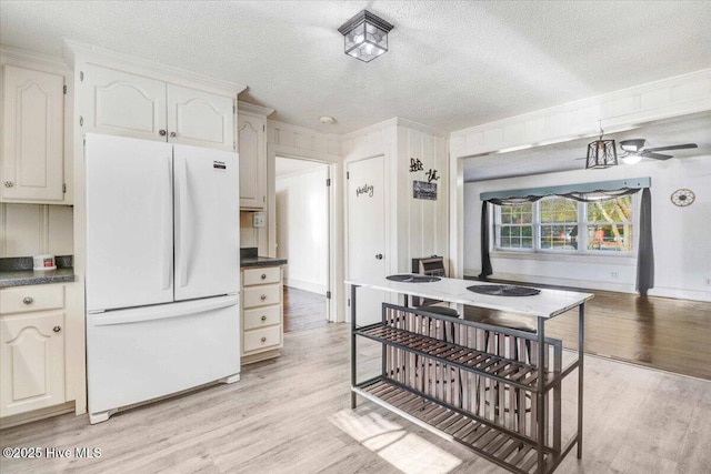 kitchen with crown molding, light hardwood / wood-style floors, a textured ceiling, and white fridge