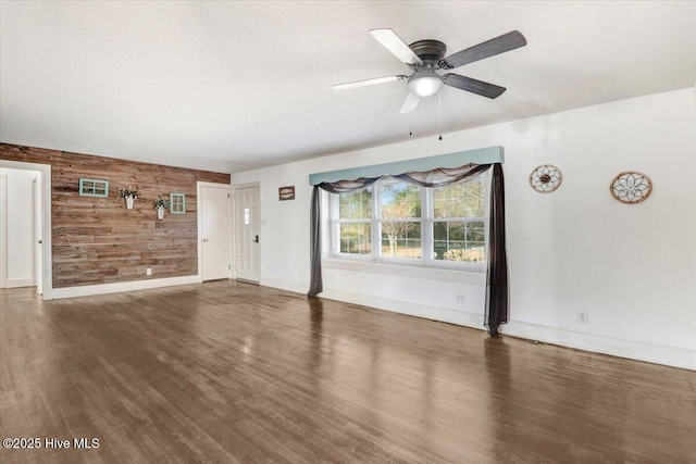 unfurnished living room featuring hardwood / wood-style flooring, ceiling fan, and wooden walls