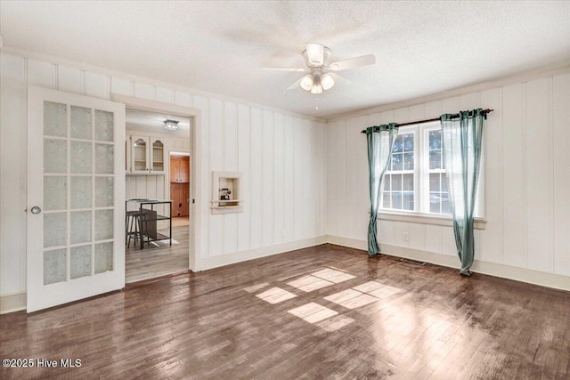 empty room with dark hardwood / wood-style flooring, a textured ceiling, ornamental molding, and ceiling fan