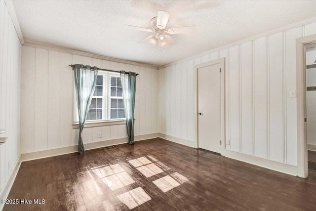 empty room featuring ceiling fan, ornamental molding, a textured ceiling, and dark hardwood / wood-style flooring