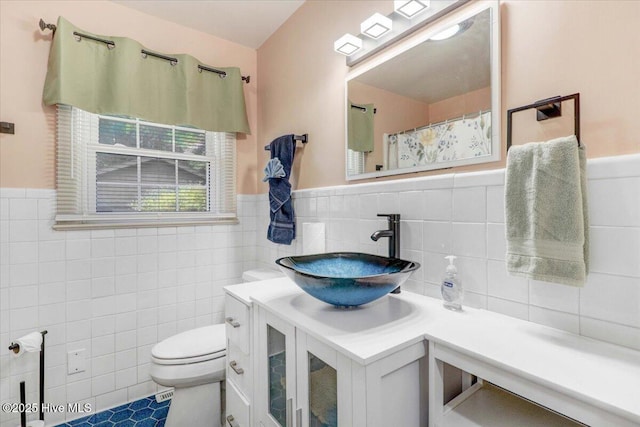 bathroom with vanity, toilet, tile patterned flooring, and tile walls