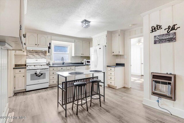 kitchen featuring heating unit, sink, white cabinets, white appliances, and light hardwood / wood-style flooring