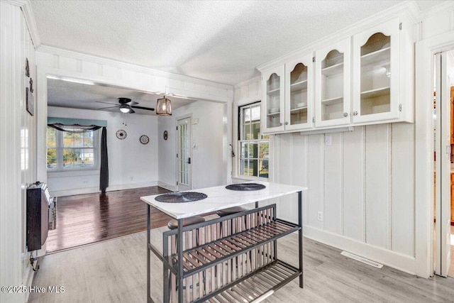 dining room featuring crown molding, a textured ceiling, and light wood-type flooring