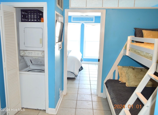 laundry room with light tile patterned flooring and stacked washer and dryer