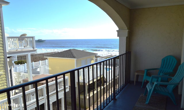 balcony with a water view and a view of the beach