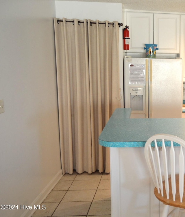 kitchen with white cabinets, stainless steel fridge with ice dispenser, and light tile patterned floors