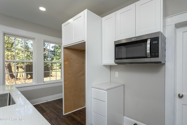 kitchen featuring dark hardwood / wood-style flooring, white cabinetry, and light stone counters