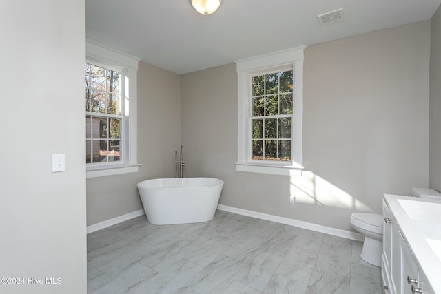 bathroom featuring plenty of natural light, toilet, a tub, and vanity