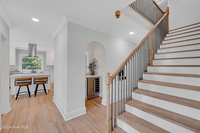 stairway with hardwood / wood-style floors, ornamental molding, and wine cooler