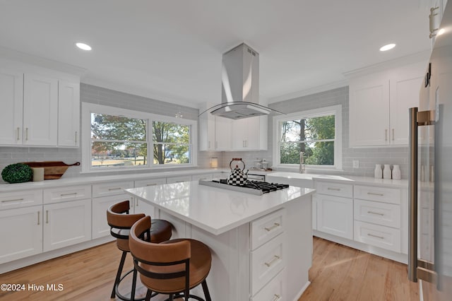 kitchen featuring white cabinets, island range hood, black gas stovetop, and light hardwood / wood-style flooring