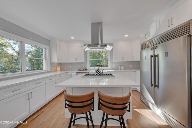 kitchen with white cabinetry, island range hood, and stainless steel built in refrigerator