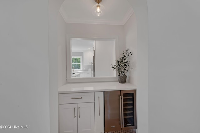 bar featuring white cabinets, ornamental molding, and beverage cooler