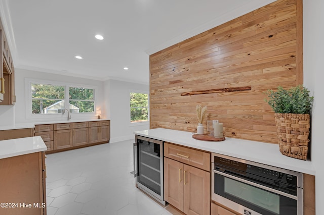 kitchen with wine cooler, wood walls, stainless steel oven, and ornamental molding