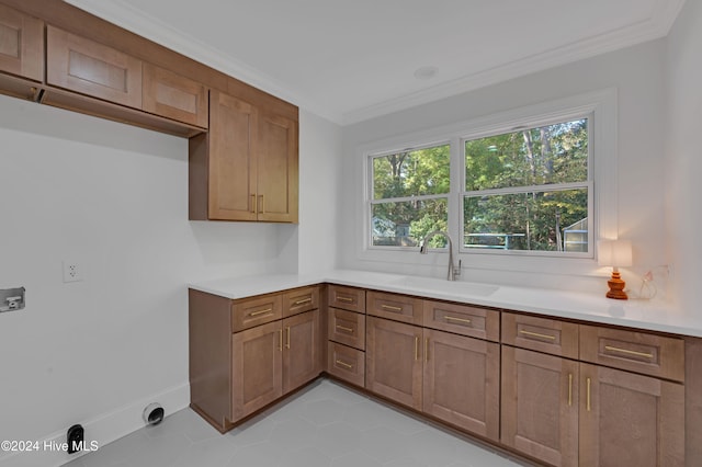 laundry area featuring cabinets, light tile patterned floors, crown molding, and sink