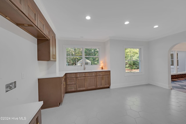 kitchen featuring sink, light tile patterned floors, and crown molding