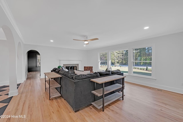 living room with ceiling fan, ornamental molding, and light hardwood / wood-style flooring