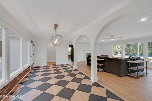 interior space with ceiling fan with notable chandelier, light wood-type flooring, and ornamental molding