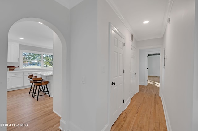 hallway with light hardwood / wood-style floors and crown molding